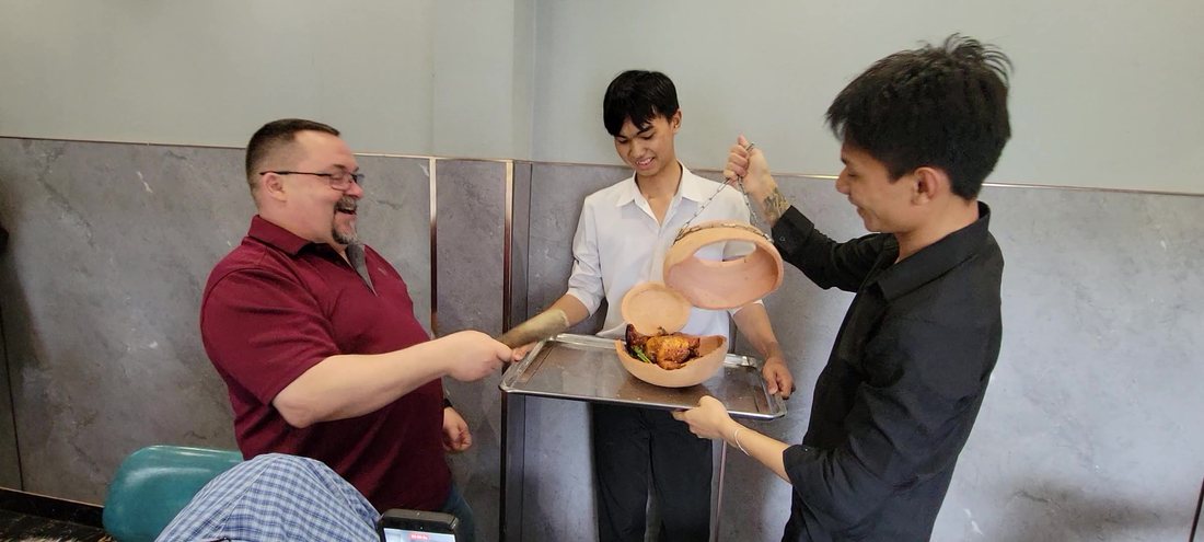 One strike. The pot splits along the shoulder ridge — the cap swings up on the chain, the bowl lands on the tray, and there is a whole roast chicken in it